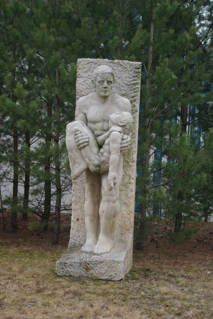 Symbolfoto einer Skulptur eines Menschen der einen hilflosen Menschen in seinen Armen trägt
