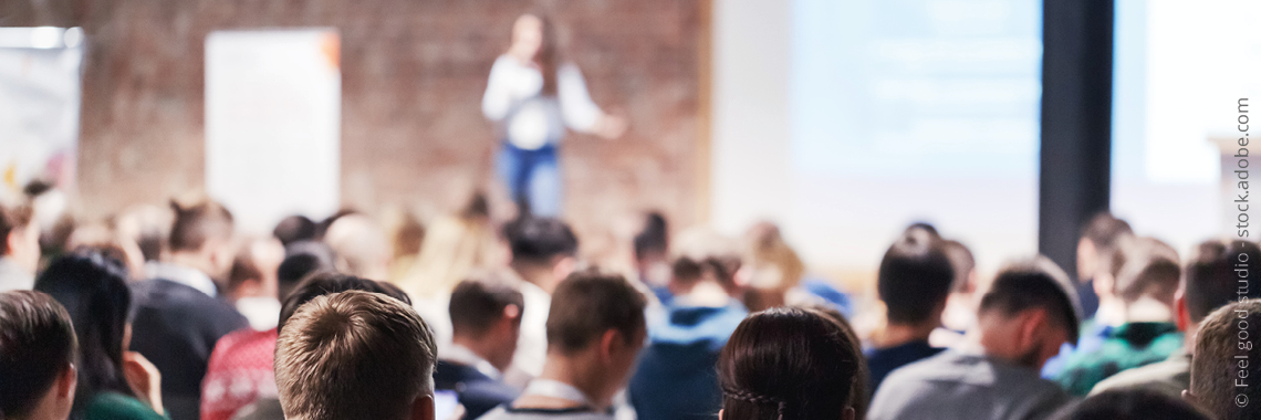 Tagungsgeschehen mit Rednerin und Teilnehmenden Copyright Foto Feel good studio - stock.adobe.com