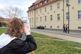 Auf dem Bild ist eine Schülerin am Theodolit zu sehen wie sie einen Punkt aufmisst.  