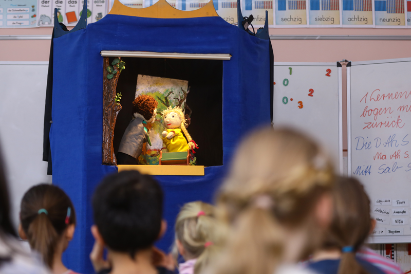 Puppenbühne mit zwei Puppen im Klassenraum vor Kindern