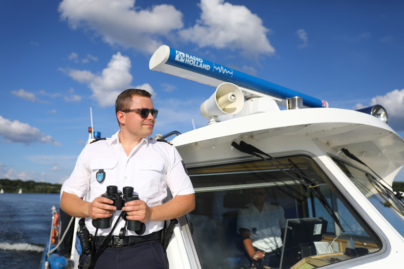 Wasserschutzpoliizist mit Fernglas während einer Kontrollfahrt