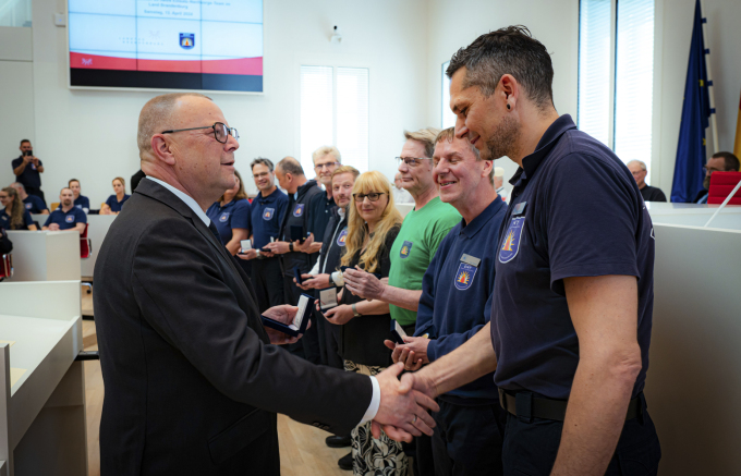 Foto von Minister Stübgen bei der Verleihung des Minister-Coins an einzelne Mitwirkende des ENT