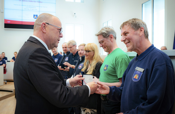 Foto von Minister Stübgen bei der Verleihung des Minister-Coins an einzelne Mitwirkende des ENT