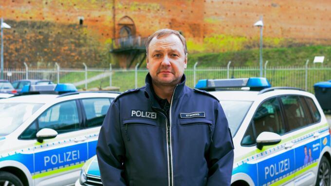 Porträtfoto Revierleiter vor Polizeiautos
