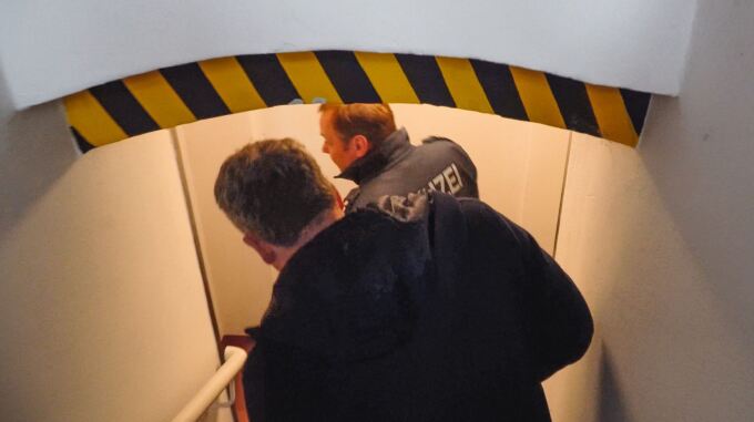 Zwei Personen laufen auf einer Treppe in einen Keller