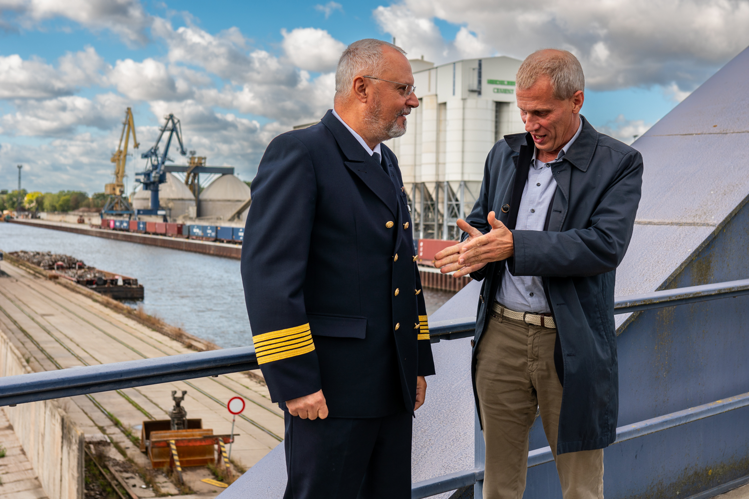 Bild: Mit Blick über den Hafen sind Wasserschutzpolizeileiter und Hafen-Geschäftsführer in Gespräch vertieft.