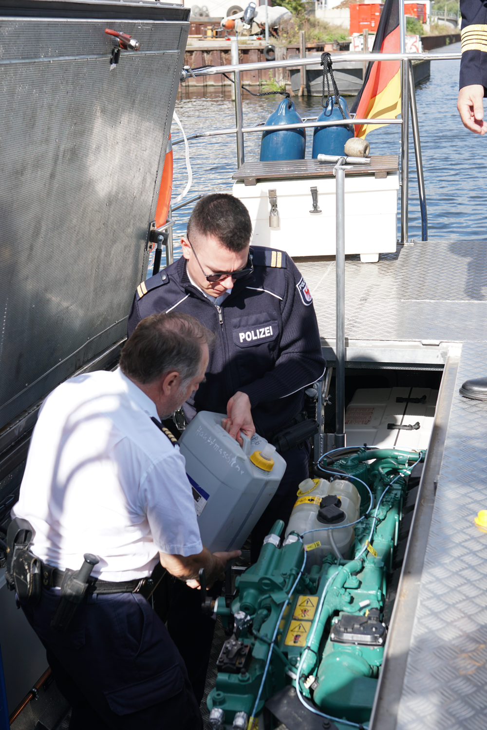 Bild: Zwei Personen füllen auf einem Boot der Wasserschutzpolizei Kühlwasser nach