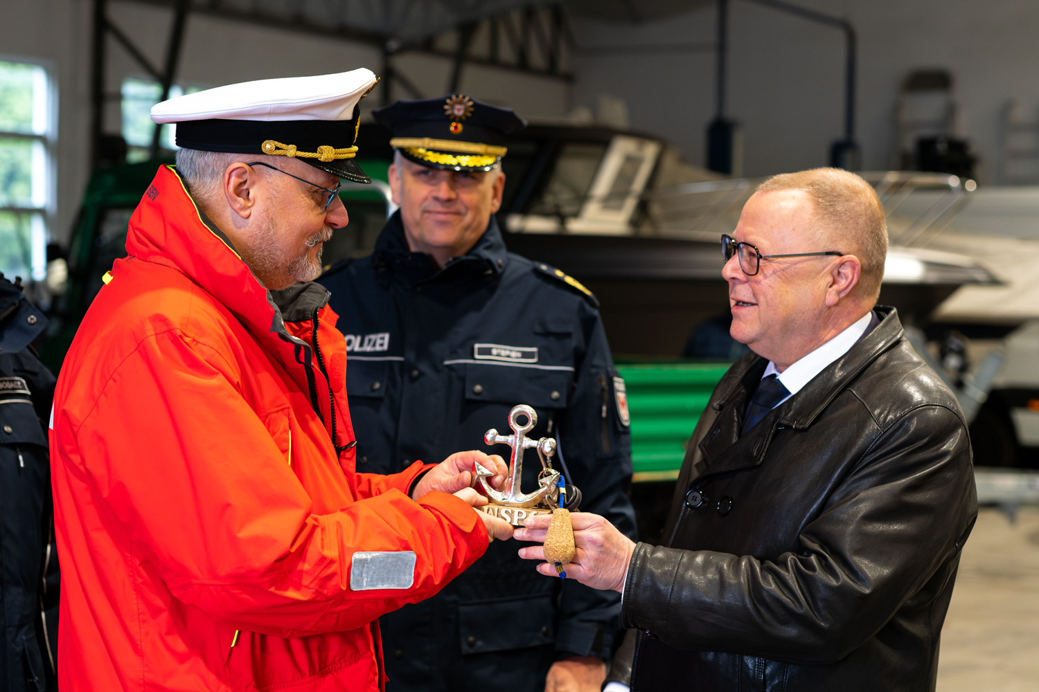 Bild: Symbolische Schlüsselübergabe des Bootes WSP6 zwischen Innenminister und Wasserschutzpolizeileiter in einer Bootshalle